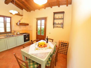 A kitchen with a dining table set for two, a wine rack, and a window with a view. - La Capannella by Interhome (Capannori)