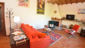 A living room with a sofa, a television, a fireplace, and a chandelier. - La Capannella by Interhome (Capannori)