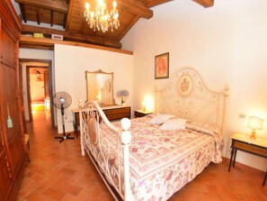 Ein Schlafzimmer mit einem Bett, einem Schminktisch, einem Spiegel, einer Deckenleuchte und einem Ventilator.
