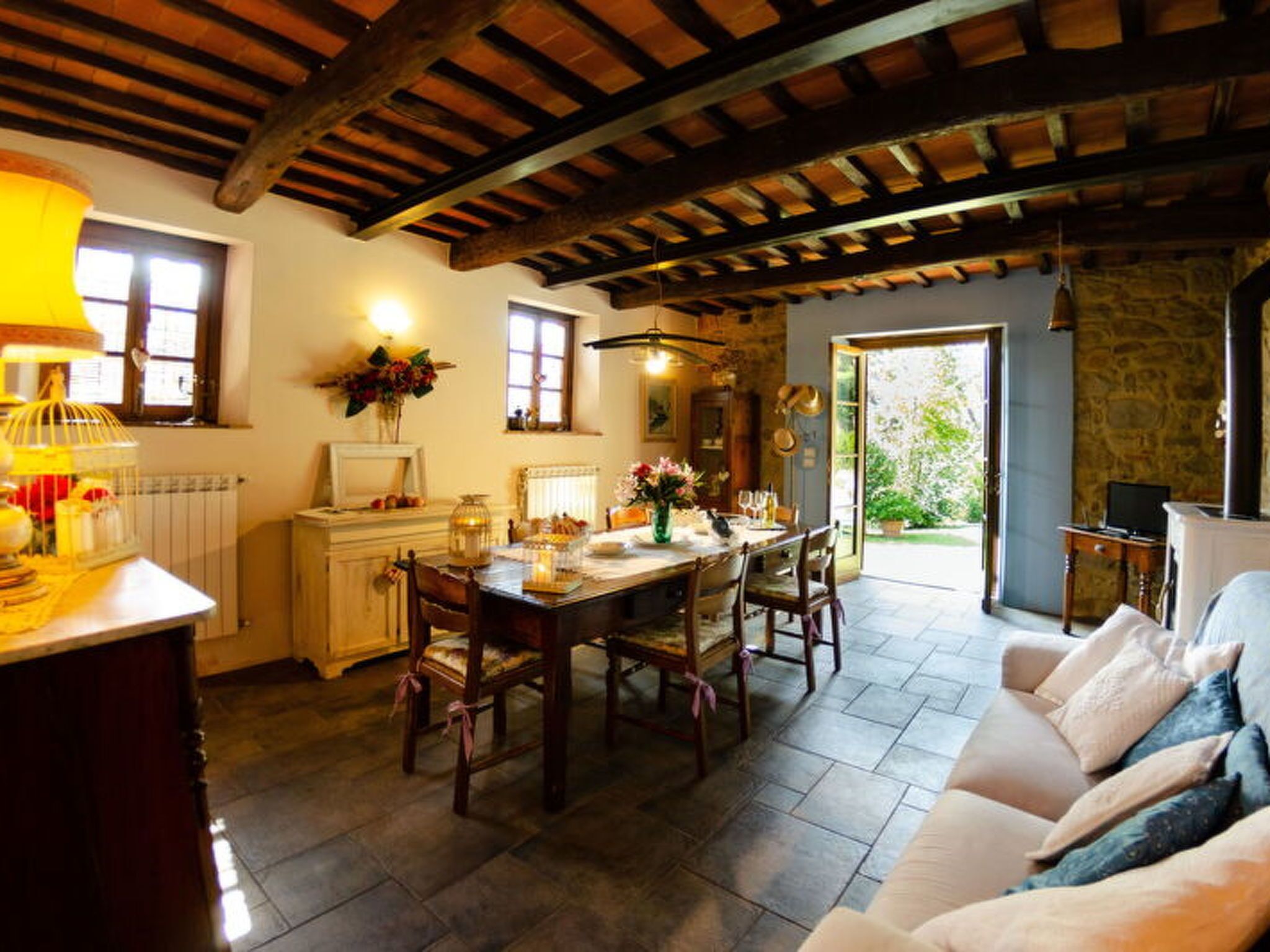 Un coin repas rustique avec une table et des chaises en bois, une cheminée en pierre et une vue sur l’extérieur.