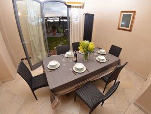A dining table set for four with chairs, a vase of yellow flowers, and a glass door leading to an outdoor area. - Al Colle Di Lari by Interhome (Lari)