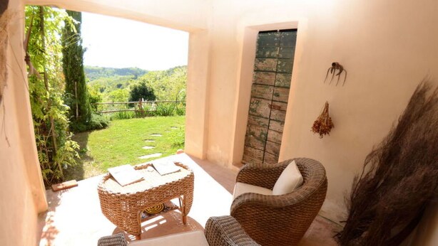A balcony with wicker furniture, a view of greenery, and a rustic door. - Al Colle Di Lari by Interhome (Lari)
