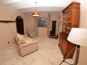 Ein Wohnzimmer mit Sofa, Schrank, Lampe, Fernseher und einem Fenster.
