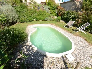 A swimming pool surrounded by gravel, with two lounge chairs and lush greenery. - Al Colle Di Lari by Interhome (Lari)