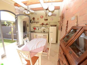 Eine kompakte Küche mit Kühlschrank, einem Esstisch mit Stühlen und einem Holzkasten mit Glastüren.