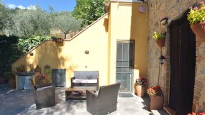 Eine Terrasse mit Korbmöbeln, einem kleinen Tisch und Blumentöpfen.