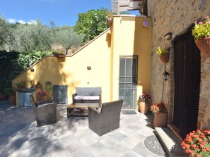 Eine Terrasse mit Korbmöbeln, einem kleinen Tisch und Blumentöpfen.