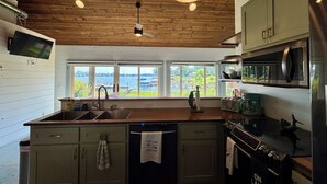 Cucina con soffitto in legno, un'ampia finestra e vista sul lago.