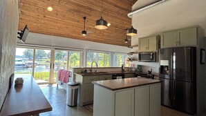 Una cucina moderna con travi in legno al soffitto, un'isola centrale e ampie finestre con vista su un corpo d'acqua.