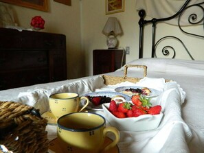 A neatly made bed with a tray of breakfast items including strawberries and a basket. - Vacation home Emilia by Interhome (Stazzema)