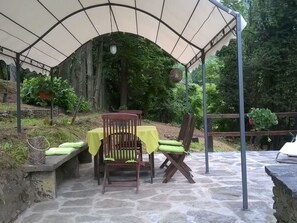 Eine Terrassengruppe mit Tisch und Stühlen unter einer Markise, umgeben von Grünpflanzen.