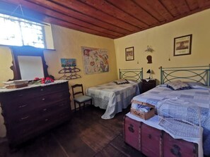 Ein Schlafzimmer mit zwei Einzelbetten, einem Schminktisch, einem Stuhl und einer Holzbalkendecke.