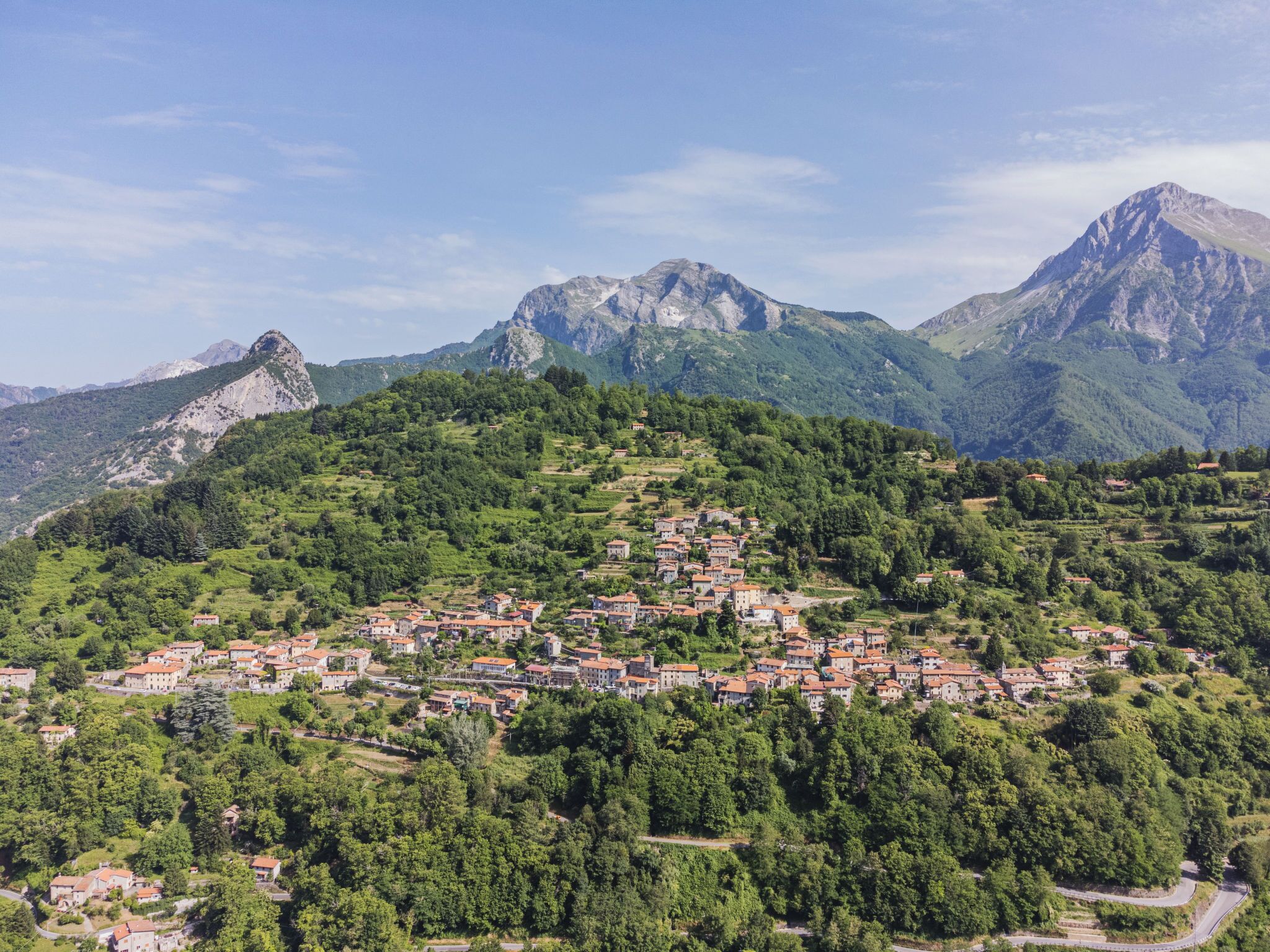 A mountainous village with terraced houses and a winding road.