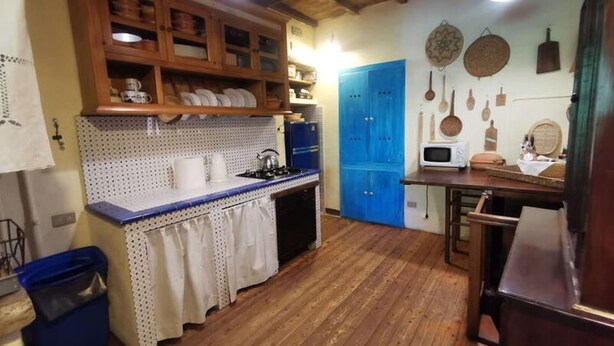 Una cocina con armarios de madera, una puerta azul y un microondas.