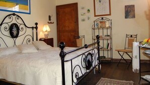 Un dormitorio con cama, puerta de madera, estante metálico y una silla.