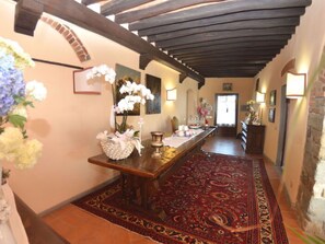 A hallway with a wooden table, a patterned rug, and a floral arrangement. - Villa Sandra Ortensia by Interhome (Casalguidi)