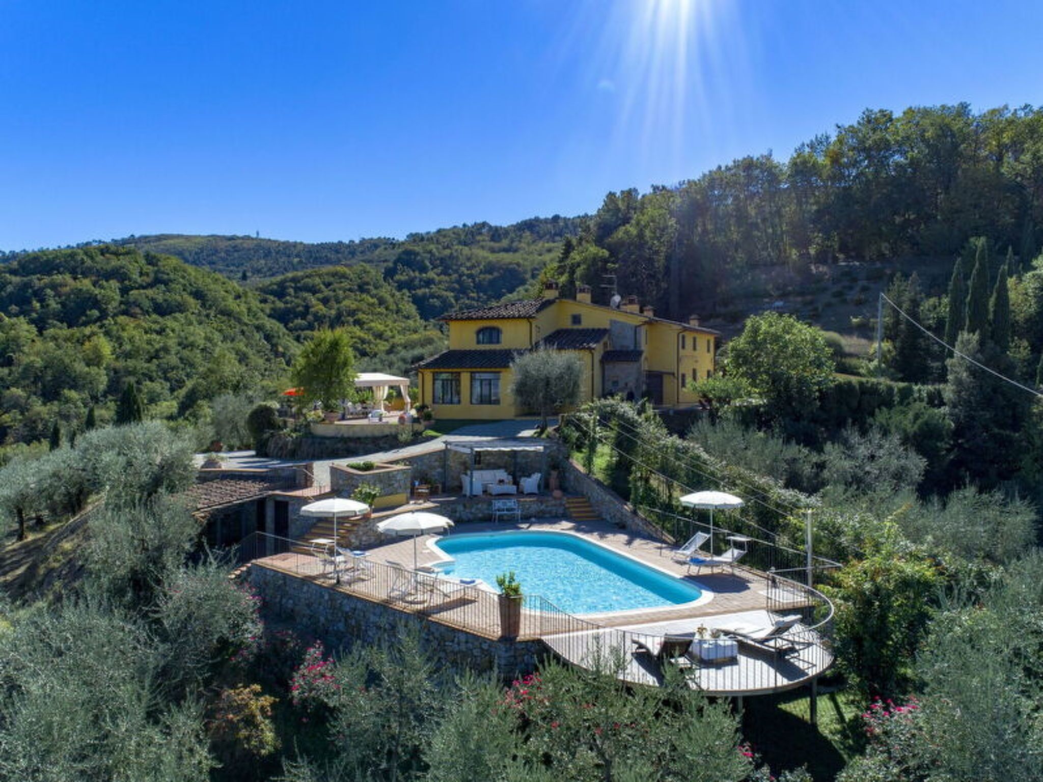 A villa with a swimming pool, outdoor seating, and a view of the surrounding hills.