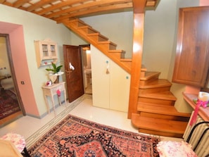 A staircase leading to a second floor, a wooden door, a small table with a plant, and a patterned rug. - Villa Sandra Ortensia by Interhome (Casalguidi)