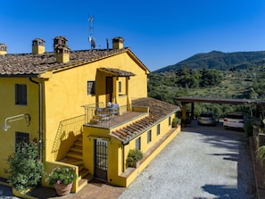 A yellow building with a balcony, a staircase, and a gravel driveway. - Villa Sandra Ortensia by Interhome (Casalguidi)