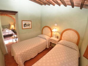 A bedroom with two beds, a nightstand, a lamp, and a framed picture on the wall. - Villa Sandra Ortensia by Interhome (Casalguidi)