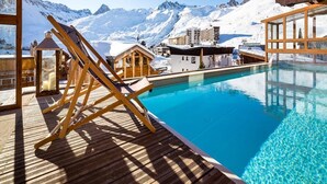 A wooden deck with a pool, wooden chairs, and a mountain view. - Les Campanules Hotel Restaurant (Tignes)