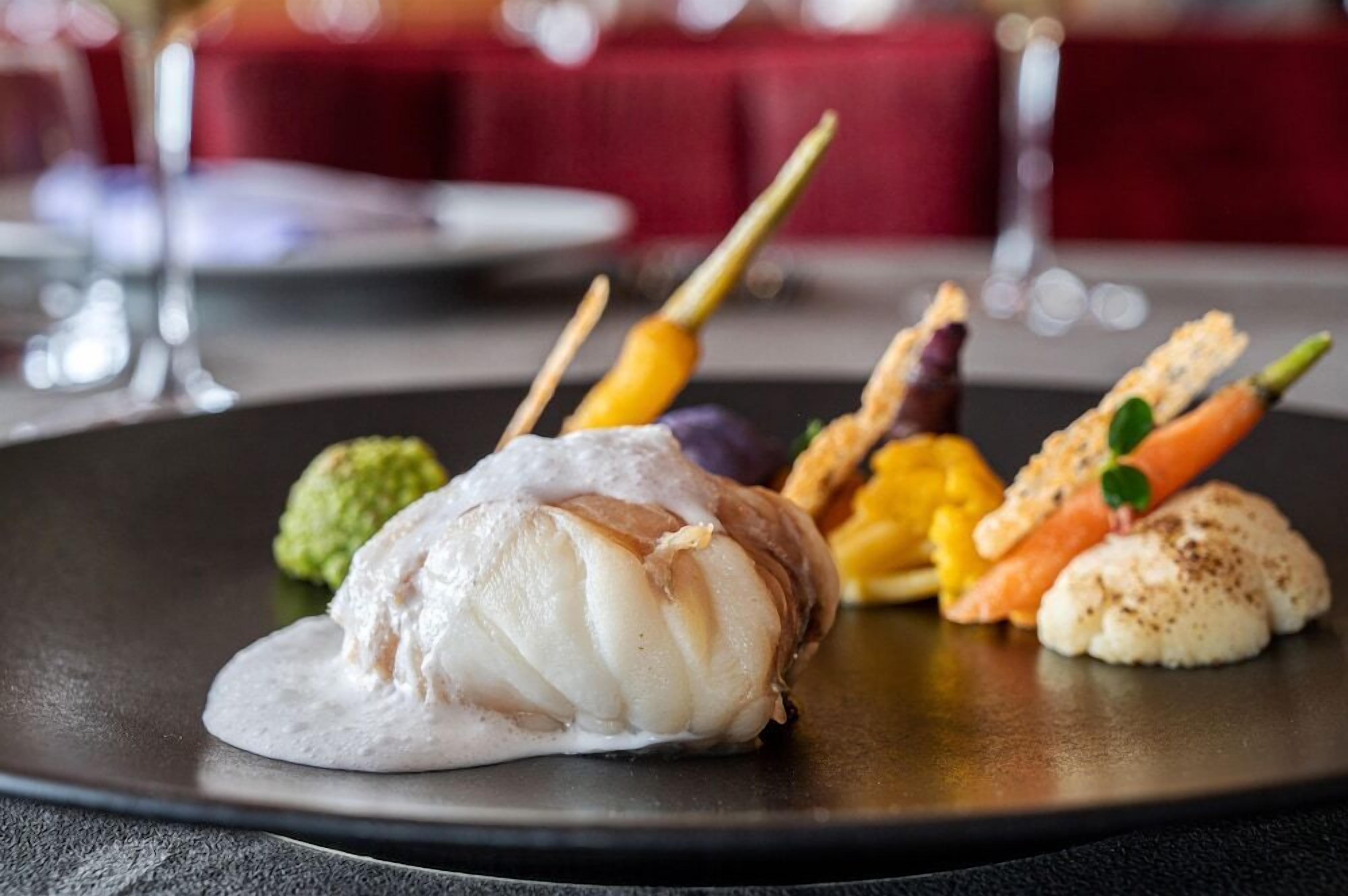 A plate of food with a fish fillet, vegetables, and a green garnish.