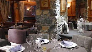 A restaurant with stone walls, tables set with wine glasses, plates, and cutlery. - Les Campanules Hotel Restaurant (Tignes)