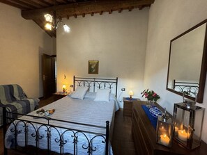 A bedroom with a bed, a chair, a bedside table with a lamp, a mirror, and a wall-mounted picture. - Podere Di Mero Casolare by Interhome (Buti)