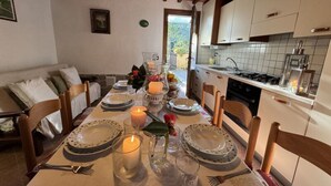 A dining table set with plates, glasses, and a candle, with a kitchen in the background. - Podere Di Mero Casolare by Interhome (Buti)