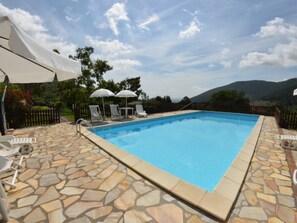 A swimming pool with stone tiles, white lounge chairs, and umbrellas. - Podere Di Mero Casolare by Interhome (Buti)