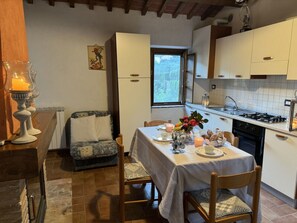 Cuina acollidora amb taula de menjador per a dues persones, una cadira i una taula petita amb una espelma.