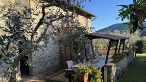 A stone building with a covered outdoor seating area, potted plants, and a view of the surrounding landscape. - Podere Di Mero Casolare by Interhome (Buti)