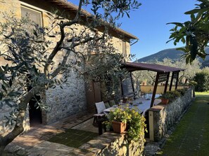 A stone building with a covered outdoor seating area, potted plants, and a view of the surrounding landscape. - Podere Di Mero Casolare by Interhome (Buti)
