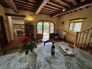 A dining area with a table set for two, a vase with flowers, and a bottle of wine. - Casa Milena by Interhome (La Sassa)