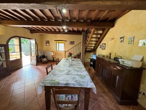 A dining area with a table, chairs, a kitchen area, and a staircase. - Casa Milena by Interhome (La Sassa)