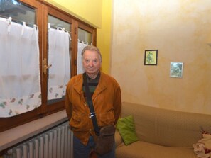 Ein Zimmer mit Fenster, Heizkörper, einer Couch und einem kleinen Bild an der Wand.