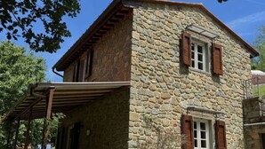A stone building with a covered porch, wooden shutters, and potted plants. - Anfora!! by Interhome (Pescia)