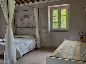 A bedroom with a bed, a window, a fire extinguisher, and a decorative wall piece. - Anfora!! by Interhome (Pescia)