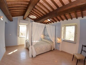 A bedroom with a four-poster bed, a window with a view, a chair, and a wooden ceiling. - Anfora!! by Interhome (Pescia)