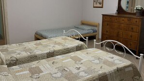 A bedroom with two beds, a wooden dresser, a mirror, and a framed picture on the wall. - Anfora!! by Interhome (Pescia)
