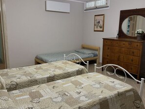 Ein Schlafzimmer mit zwei Betten, einem hölzernen Schminktisch, einem Spiegel und einem gerahmten Bild an der Wand.