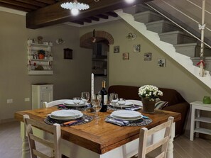 Ein Essbereich mit einem Holztisch, gedeckt für vier Personen, einer Treppe und einem kleinen Beistelltisch mit Blumen in einer Vase.