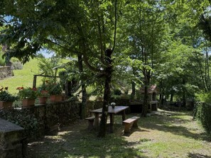 An outdoor garden area with stone walls, wooden benches, and potted plants. - Anfora!! by Interhome (Pescia)