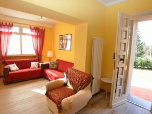 A room with a red sofa, a beige armchair, a small table, and a door leading outside. - Borgo Di Zacco by Interhome (La Sassa)