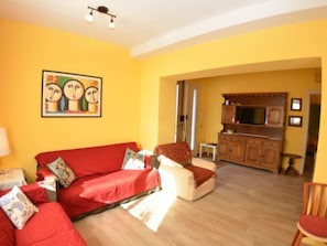 A living room with a red sofa, a chair, a wooden cabinet, and a painting on the wall. - Borgo Di Zacco by Interhome (La Sassa)