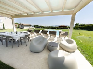 Eine Außenpatio mit überdachter Sitzgelegenheit, einem Pool und Blick auf die umliegende Landschaft.