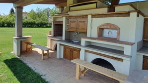 Una cocina al aire libre con una parrilla empotrada, armarios de madera y encimera de piedra.