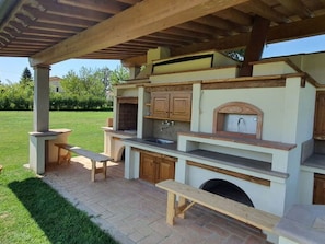 Eine Außenküche mit integriertem Grill, Holzschränken und einer Steinarbeitsplatte.