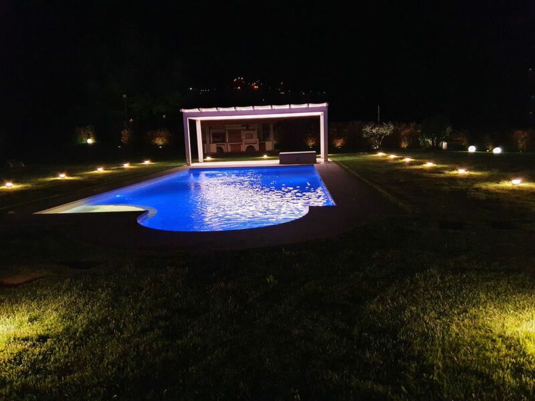 Ein Schwimmbecken mit überdachtem Bereich und umlaufender Beleuchtung.
