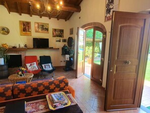 A living room with a fireplace, a sofa, a television, and a door leading outside. - La Capannella Del Cinema by Interhome (Capannori)